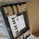 V krabici s hnědými papírovými vložkami je umístěn kompaktní MIDI kontrolér s klávesnicí. Na zařízení je vidět bílý nápis AKAI a model MPK mini. Přes…