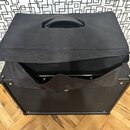 Černý kytarový kombozesilovač s černou textilní ochrannou krycí plachtou, která je mírně odsunuta dopředu. Na horní části plachty je integrovaná úchy…