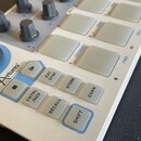 Detailní pohled na ovládací panel bílého elektronického nástroje. Na modrém podkladu je vidět logo Arturia a nápis LEVEL/RATE u velkého černého knofl…