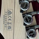 Detail hlavy kytary z jasného dřeva s viditnou masivním zrnitostí. Na zadní straně je nápis MADE IN JAPAN, sériové číslo F2330762 a rámeček s certifi…