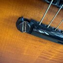 Detailní pohled na černý plastový kobylník akustické kytary s nylonovými strunami. Na konci kobylníku je viditelný prask v materiálu u upevňovacího p…