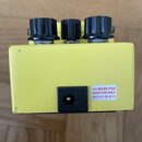 Žlutý efekt pedál s třemi černými oválnými knoflíky. Na zadní straně je černý vstup pro napájení a bílá nálepka s červeným textem USE BOSS PSA ADAPTO…