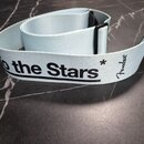 Světle modrý textilní popruh k hudebnímu nástroji s černými plastovými prvky. Na popruhu je černý nápis „to the Stars“ a logo „Fender“. Povrch popruh…