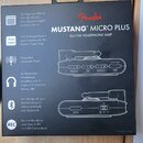 Fotografie znázorňuje černé originální balení sluchátkového zesilovače. Na krabici je červené logo Fender a bílý nápis MUSTANG™ MICRO PLUS GUITAR HEA…