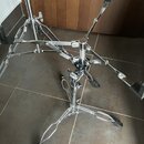 Stříbrný kovový stojan s trojramennou základnou a černými gumovými koncovkami. Konstrukce obsahuje několik nastavovacích šroubů a klouzevých mechanis…