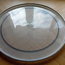 Kruhové elektronické čelo nebo perkuse s průhlednou membránou a stříbrným kovovým rámem. V horní části membrány je modré logo s nápisem DW Percussion…