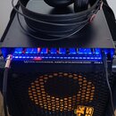 Na černém basovém kombu Markbass je položen černý zesilovač s modrým podsvícením ovládacího panelu. Na přední straně zesilovače je nápis WARWICK AMPL…