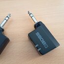 Dvě černé redukce s kovovými konektory typu jack. Na obou je bílý nápis BOSS s doprovodným logem. Na pravém kusu je svisle napsán text POWER READING.…