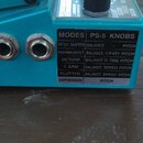 Detailní pohled na tyrkysový efekt pedál. Na boku je viditelná tabulka s nápisy MODES, PS-5 KNOBS a seznamy funkcí jako PITCH SHIFTER, HARMONIST, DET…