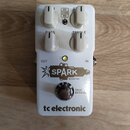 Bílý efekt pedál s nápisy SPARK BOOSTER a tc electronic. Na horní straně jsou čtyři bílé otočné ovladače s popisky BASS a TREBLE, doprovázené přepína…