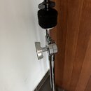 Fotografie znázorňuje horní část chromovaného mikrofonního stojanu. V horní části je černý plastový držák s černou pěnovou clonou. Na stojanu není vi…