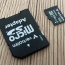 Černý adaptér SD karty s bílým nápisem Micro Adapter a logem verbatim. Vedle něj je umístěna malá černá microSD karta s nápisy Verbatim, Premium, 16G…