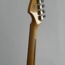 Zadní strana krku a hlavy elektrické kytary z přírodního dřeva. Na zadní straně hlavy je nápis „Designed & Patented by Fender“ a sériové číslo „US 12…