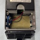 Fotografie zachycuje otevřený zadní prostor elektronického zařízení s viditelným vnitřkem. Na horním černém plastovém panelu je bílý nápis 450417 a t…