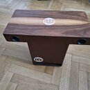 Hnědý dřevěný cajon s tmavším povrchem a světlým pruhem uprostřed horní desky. Na horní desce i na spodní části je bílé kulaté logo s nápisem MEINL.…