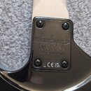 Detail zadní strany krku a spoje s tělem černé elektrické kytary. Na černém plastovém krytu je logo Jackson, sériové číslo GWJ2424204 a nápis CRAFTED…