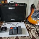 Na fotografii je elektrická kytara s barevně přechodovým lakem od žluté po tmavě hnědou, černým vzorovaným pickguardem a světle barevnými knoflíky. V…