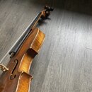 Housle z dřeva s žlutohnědým lakem. Nástroj vykazuje známky opotřebení v podobě odřenin a odsloupání laku, zejména na hranách korpusu. Na fotce nejso…