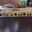 Zadní panel hnědého komba značky FISHMAN. Panel obsahuje napájecí vstup, přepínač, vstupy Foot Switch a Aux Input, výstup Mix D.I. Out a sekce Effect…