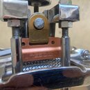 Detailní pohled na mechanismus napínání snare drumu. Na měděně barevné součástce je vyryt nápis PURESOUND™. Součásti jsou vyrobeny z kovu v chromovém…