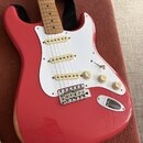 Červená elektrická kytara typu Stratocaster s bílým pickguardem a javorovým hmatníkem. Nástroj má tři bílé snímače, jeden přepínač a tři otočné poten…