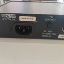 Zadní strana černého elektronického zařízení s nápisy MPX 500 a LEXICON, INC. Na šasi jsou bílé nálepky s texty Made in P.R.C a LCD CONTRAST, dále ná…