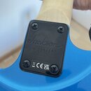 Detail zadní strany modré elektrokytary v místě spoje krku s tělem. Černý krycí kryt s nápisem Jackson, sériovým číslem CWJ2264260 a označením CRAFTE…