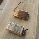 Dvě elektrické kytarové snímače typu humbucker v pozlaceném provedení. Snímač v horní části má hladký kryt s viditelnými šrouby, spodní snímač má kry…