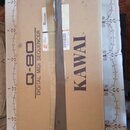 Hnědý kartonový obal s nápisy KAWAI, Q-80 a DIGITAL MIDI SEQUENCER. Na krabici je viditelný bílý štítek s čárovým kódem a číslem 402345266. Celý bale…