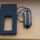 Fotografie zobrazuje sadu snímačů pro elektrickou kytaru a příslušenství. Jsou zde dva černé humbuckery s nápisem Seymour Duncan, jeden z nich má stř…