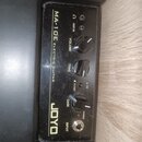 Černý kytarový kombozesilovač s nápisy MA-10E ELECTRIC GUITAR a JOYO. Ovládací panel obsahuje tři černé otočné knoflíky s popisky VOLUME, TONE a GAIN…