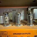 Fotografie zachycuje vnitřek zesilovače s třemi elektronkami v kovových paticích. Na spodním žlutém panelu je nápis SPEAKER OUTPUTS a tři výstupy ozn…