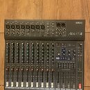 Šedý mixovací pult značky YAMAHA, model Mx12/4. Horní panel obsahuje vstupy, konektory a ovládací prvky s nápisy jako INPUT, GAIN, HIGH, LOW, MON a E…