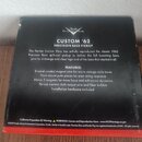 Černá čtvercová krabička s bílým textem. V horní části je logo Fender Custom Shop a nápis CUSTOM '62 PRECISION BASS PICKUP. Následuje popis produktu…
