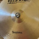 Zlatý kovový činel s viditelným opracováním povrchu. V horní části je černý nápis istanbul® a pod ním kurzívou Mehmet Handmade Cymbals from Turkey. V…