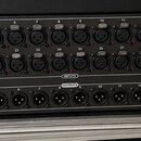 Černý digitální stagebox s řadou vstupů a výstupů. Na předním panelu jsou nápisy behringer, S32 POWERED BY MIDAS a AESO SYNC. Horní část obsahuje 32…