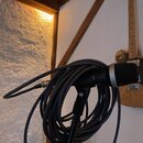 Černý dynamický mikrofon s kovovou síťkou v horní části, umístěný na černém mikrofonním stojanu. K mikrofonu je připojena dlouhá, srolovaná černá kab…