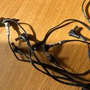 Kumpulan černých napájecích kabelů s konektory typu DC jack. Na dvou kabelech jsou bílé papírové štítky s nápisy „9V DC“ a „200 mA“. Kabely leží na d…