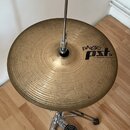 Zlatý činel osazený na chromovaném stojanu s pedálem. Na povrchu činelu je černý nápis paiste PST 15" MEDIUM HI-HAT (646). Povrch činelu vykazuje jem…