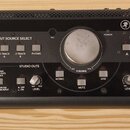 Černý monitor kontroler s nápisem BIG KNOB STUDIO COMMAND SYSTEM. Zařízení obsahuje centrální ovladač VOLUME, sekce INPUT SOURCE SELECT s tlačítky DA…