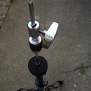 Fotografie zachycuje horní část černého stativu s kovovým, chromovaným mechanismem pro upevnění nástroje. Na chromované části je vidět šroub s velkým…