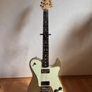 Zlatá elektrická kytara s bílým pickguardem a černým hmatníkem. Na hlavě je nápis Fender TELECASTER DELUXE. Nástroj má dva humbuckery, tři ovládací k…
