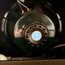 Zadní pohled na reproduktor v tmavě zelené barvě. Uprostřed je bílá kulatá nálepka s modrým okrajem, na které je nápis Fender, N12K 8Ω, mfd by JENSEN…