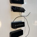 Čtyři černé elektrické snímače kytary v plastovém provedení. Dva z nich jsou typu humbucker s viditelnými kovovými póly, další dva mají hladký povrch…
