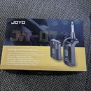 Krabice s bezdrátovým systémem, na které je nápis JOYO a model JW-07. Text na obalu uvádí „2.4G Digital Wireless System“ a seznam technických paramet…