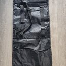 Černý obdélníkový obal z syntetického materiálu s jemným leskem. V horní části jsou dvě černé popruhy s plastovými přezkami a šitými úchyty. Povrch m…