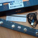 Černý obdélníkový MIDI kontrolér s nápisy M-VAVE, USB, HOST a PEDAL. Zařízení má čtyři kovové spínače označené písmeny A, B, C a D, digitální displej…