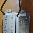 Dvě elektrické humbucker snímače s kovovými kryty a mosaznými póly. Na obou jsou bílé nálepky s nápisy „11ZEZ 20180810“ a sériovým číslem „S/N 082118…
