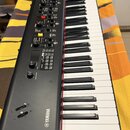 Černý digitální klavír s bílými a černými klávesami. Na levé straně korpusu je bílý nápis YAMAHA s doprovodným logem. Ovládací panel obsahuje různé t…