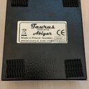 Fotografie zachycuje spodní stranu černého efektpedálu s texturovaným povrchem. V rozích jsou nalepené čtyři černé suché vrstvy (velcro). Uprostřed j…